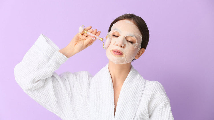Woman applying facial mask with applicator against a purple background